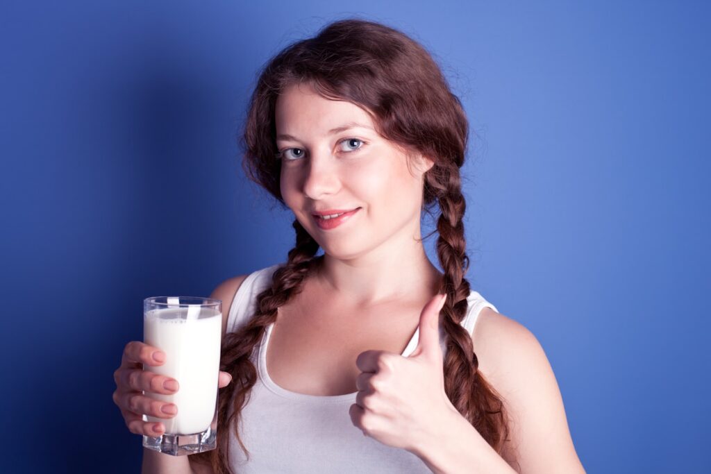 A woman is holding a glass of milk